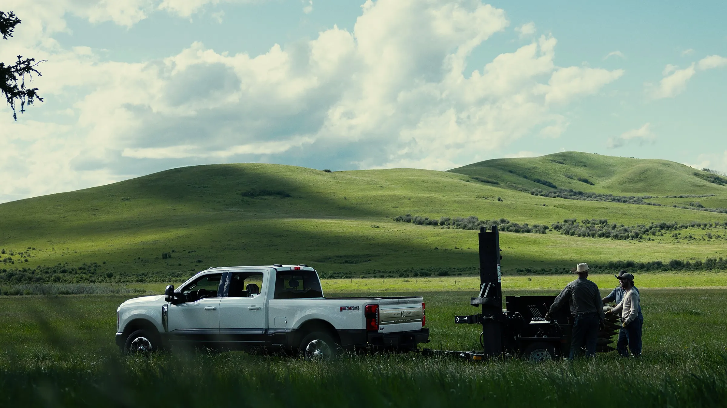 A Ford Super Duty® F-350® King Ranch® towing a trailer through a grassy field